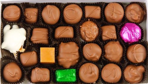 A variety of assorted chocolates in a box, featuring different shapes and colorful wrappers.