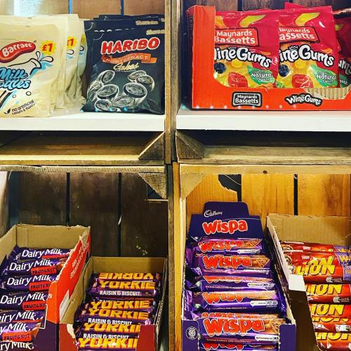 Shelves filled with various candy and chocolate bars, including Haribo, Wine Gums, and Dairy Milk products.