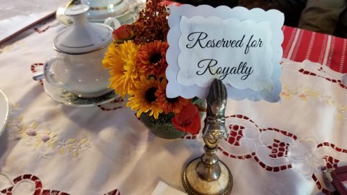 A table setting with a floral centerpiece and a sign that reads "Reserved for Royalty."