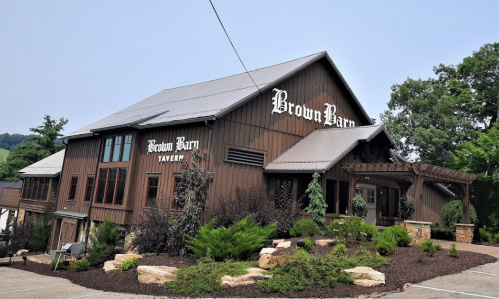 Exterior of the Brown Barn Tavern, featuring a wooden facade and landscaped surroundings.