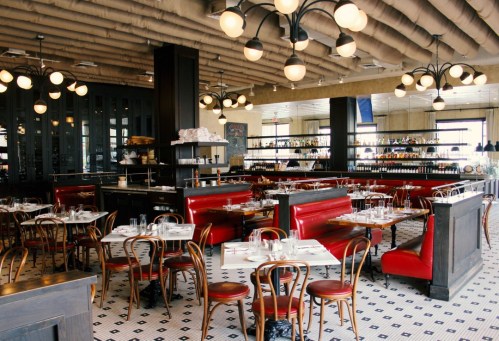 A stylish restaurant interior featuring red booths, wooden tables, and modern lighting fixtures.