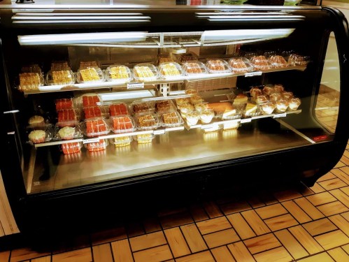 A display case filled with various baked goods, including pastries and desserts, in a bakery setting.