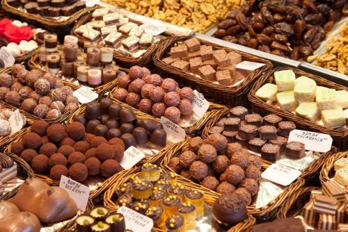 A variety of chocolates and confections displayed in woven baskets, including truffles, pralines, and chocolate-covered treats.