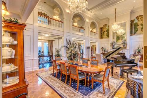 Elegant dining room with a grand piano, chandelier, and ornate decor, featuring a large table and stylish furnishings.