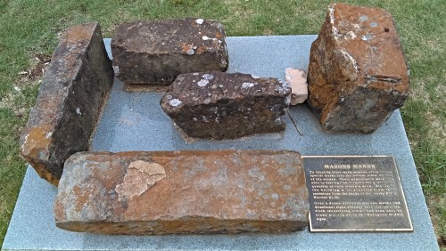 Five weathered stone blocks arranged on a grassy surface, accompanied by an informational plaque.