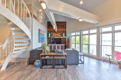 Modern living room with a spiral staircase, large windows, and a cozy seating area overlooking a lake.