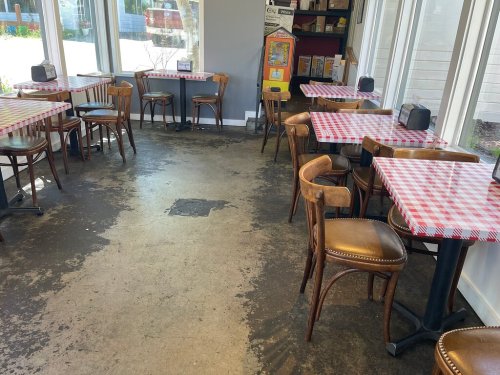 Interior of a restaurant with checkered tablecloths, wooden chairs, and a clean, bright atmosphere.