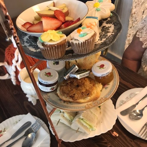 A tiered stand with fruit, cupcakes, cookies, sandwiches, and pastries, set for afternoon tea.