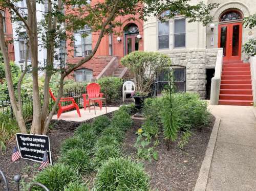 A garden with red chairs, a white chair, and a sign reading "Injustice anywhere is a threat to justice everywhere."