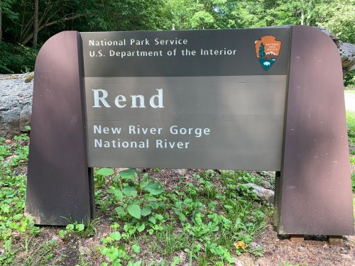Sign for Rend, New River Gorge National River, with National Park Service logo and greenery in the background.