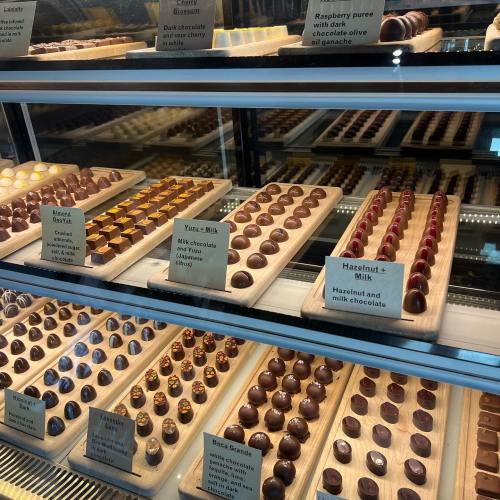 A display case filled with assorted chocolates, labeled with flavors like raspberry, hazelnut, and yuzu.