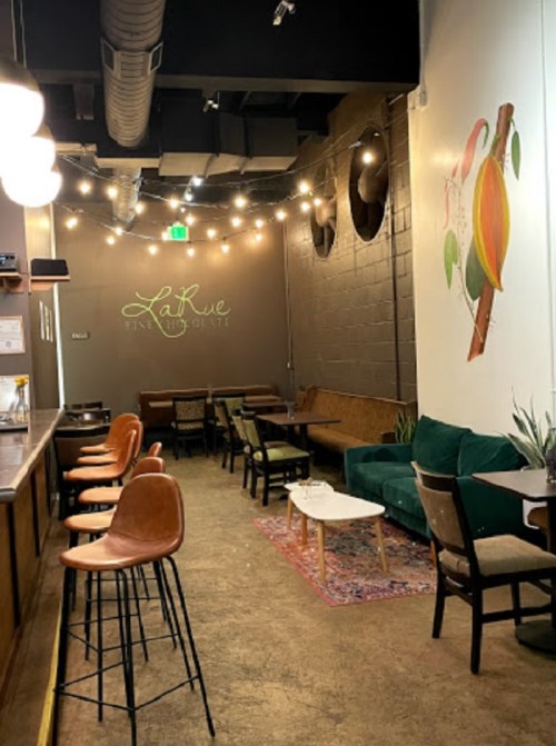Cozy café interior with green seating, warm lighting, and decorative wall art, creating a welcoming atmosphere.