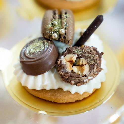 A close-up of a decorated dessert featuring chocolate, cream, and a variety of sweet toppings on a cookie base.