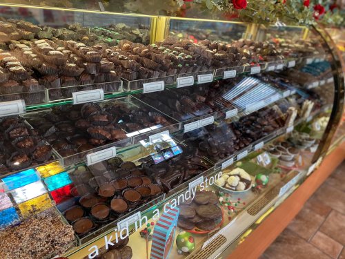 A display case filled with various chocolates and candies, showcasing an assortment of treats in a candy store.