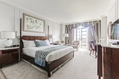 A stylish hotel room featuring a large bed, elegant decor, and a window with a view.