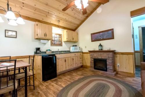 Cozy cabin interior featuring a kitchen, dining area, and a stone fireplace with wooden accents and a rustic feel.