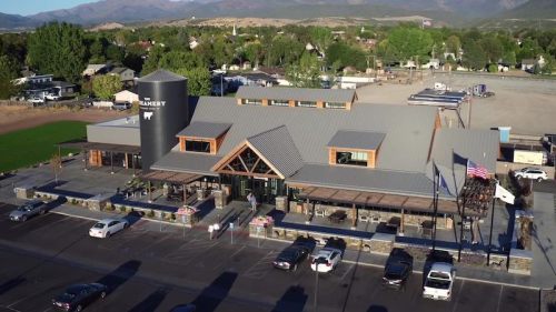 Aerial view of a modern building with a large outdoor patio, surrounded by trees and mountains in the background.