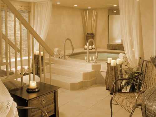 A serene spa interior featuring a hot tub, candles, and bamboo decor, creating a relaxing atmosphere.