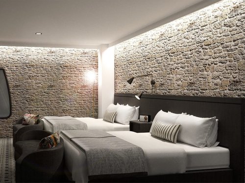 Modern hotel room with two beds, stone accent wall, and stylish lighting. Cozy seating area included.