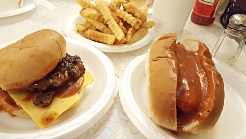 A plate with a cheeseburger and a hot dog, accompanied by a side of crinkle-cut fries.