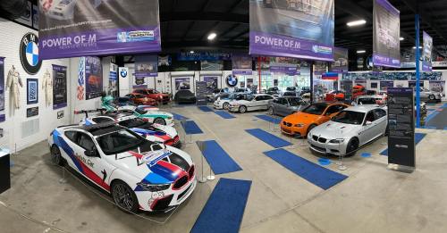 A spacious car showroom featuring various BMW models, including sports cars and classic designs, with banners and displays.