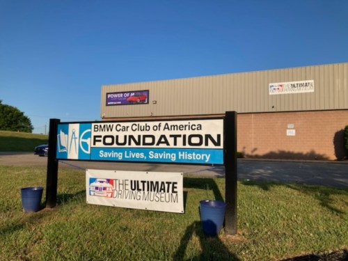 Sign for the BMW Car Club of America Foundation and The Ultimate Driving Museum, set against a blue sky.