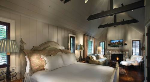 Cozy bedroom with a large bed, fireplace, and comfortable seating, featuring warm lighting and rustic decor.