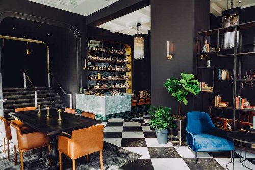 Chic interior of a modern bar with a black and white checkered floor, elegant seating, and a well-stocked bar.