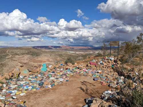 A scenic overlook with colorful painted rocks, surrounded by mountains and a cloudy sky.