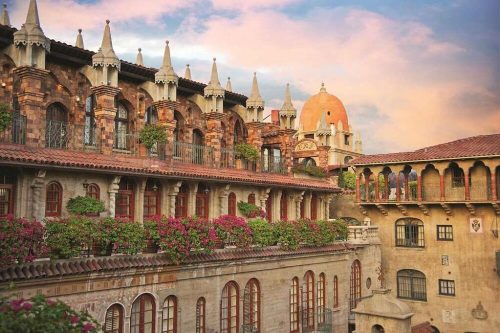 Historic buildings with ornate architecture and vibrant flowers under a colorful sky at sunset.