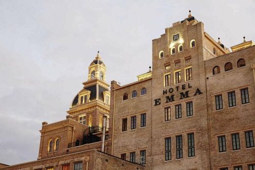 Historic Hotel Emma with a distinctive dome and elegant brick facade, bathed in warm light against a cloudy sky.