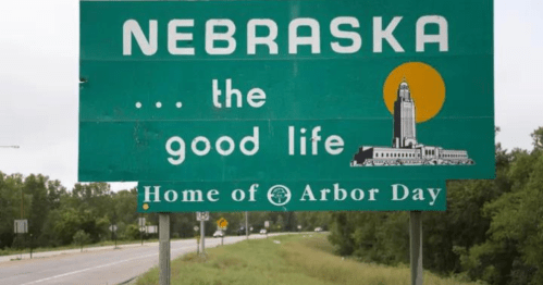 Green Nebraska welcome sign featuring the state motto "the good life" and "Home of Arbor Day."