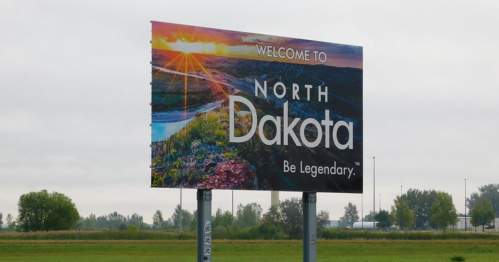 A welcome billboard for North Dakota featuring a sunset and the slogan "Be Legendary."