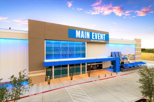 Exterior of Main Event Entertainment building with blue accents and a welcoming entrance. Clear sky in the background.