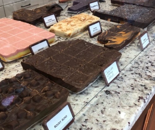 A display of various chocolate treats on a marble counter, labeled with flavors like Rocky Road and others.