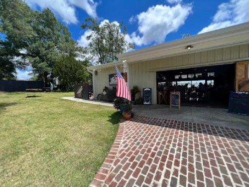 A sunny outdoor view of a building with a brick path, featuring an American flag and green grass.