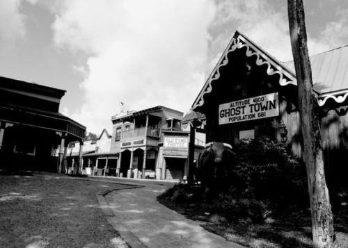 Black and white image of a deserted ghost town with old buildings and a sign indicating a population of 681.