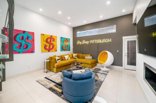 Modern living room with yellow sectional, blue chair, dollar sign artwork, and neon "Stay Classy Pittsburgh" sign.