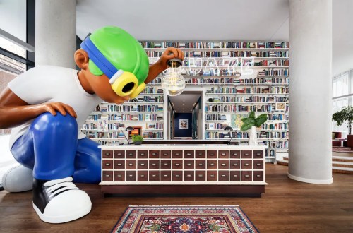 A large cartoon figure with a green cap kneels beside a modern reception desk in a library-themed lobby.