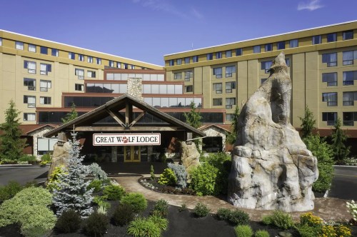 Exterior view of Great Wolf Lodge, featuring a stone entrance and landscaped surroundings with trees and flowers.