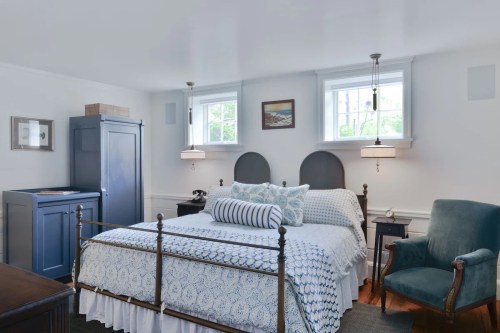Cozy bedroom featuring a metal bed, blue accents, two windows, and a comfortable armchair.