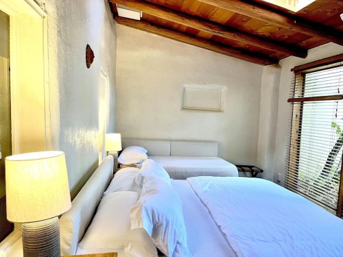 Cozy bedroom with a double bed, a single bed, wooden ceiling, and natural light from a window.