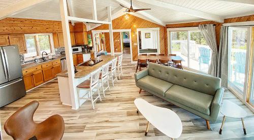 Bright, modern open-concept living space with a kitchen, dining area, and comfortable seating. Large windows let in natural light.