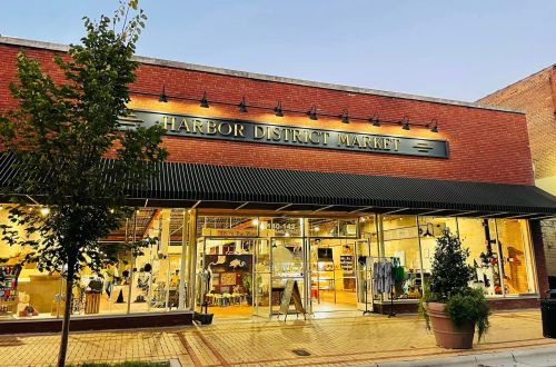 Exterior of Harbor District Market, featuring large windows and a welcoming entrance, set in a brick building at dusk.