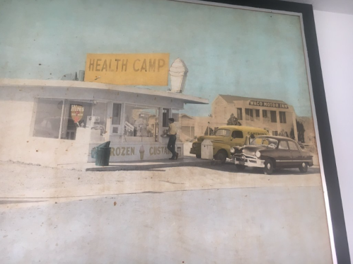 A vintage photo of a roadside ice cream stand called "Health Camp" with classic cars parked outside.