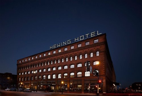 Hewing Hotel exterior at night, showcasing its brick facade and illuminated sign against a dark sky.