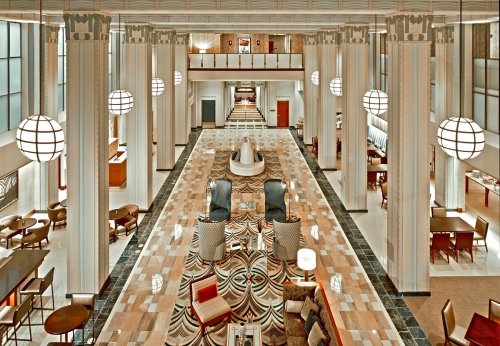 Elegant hotel lobby featuring tall columns, modern lighting, and stylish seating areas with a patterned floor.