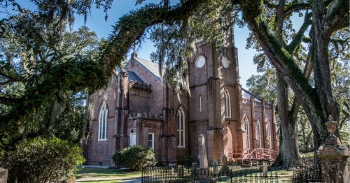 Grace Episcopal Church in St. Francisville, LA, showing historic brick church and steeple surrounded by spanish moss