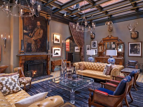 Elegant living room with leather sofas, a fireplace, artwork, and decorative accents, featuring a warm, inviting atmosphere.