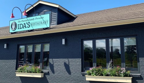Exterior of Ida's Restaurant featuring a blue facade, large windows, and flower boxes under a clear sky.